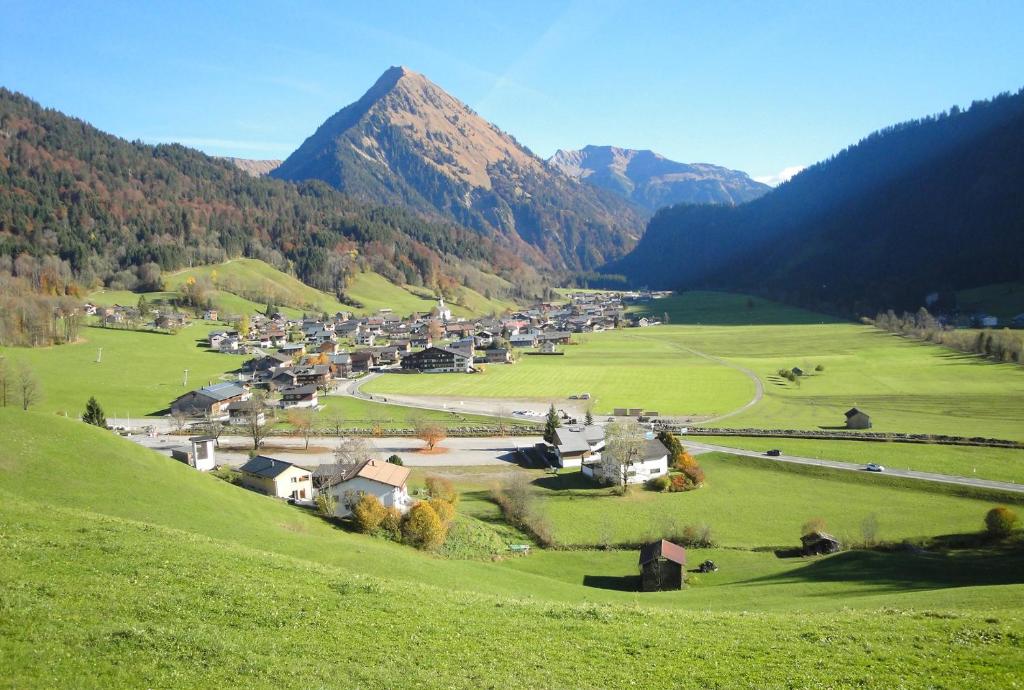 a small village in a field with mountains in the background at Fernblick Frühstückspension in Schoppernau