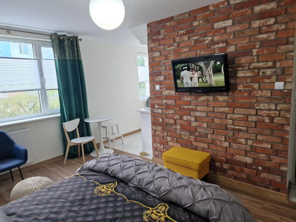 a bedroom with a brick wall with a tv on the wall at Kawalerka na pierwszym piętrze in Malbork