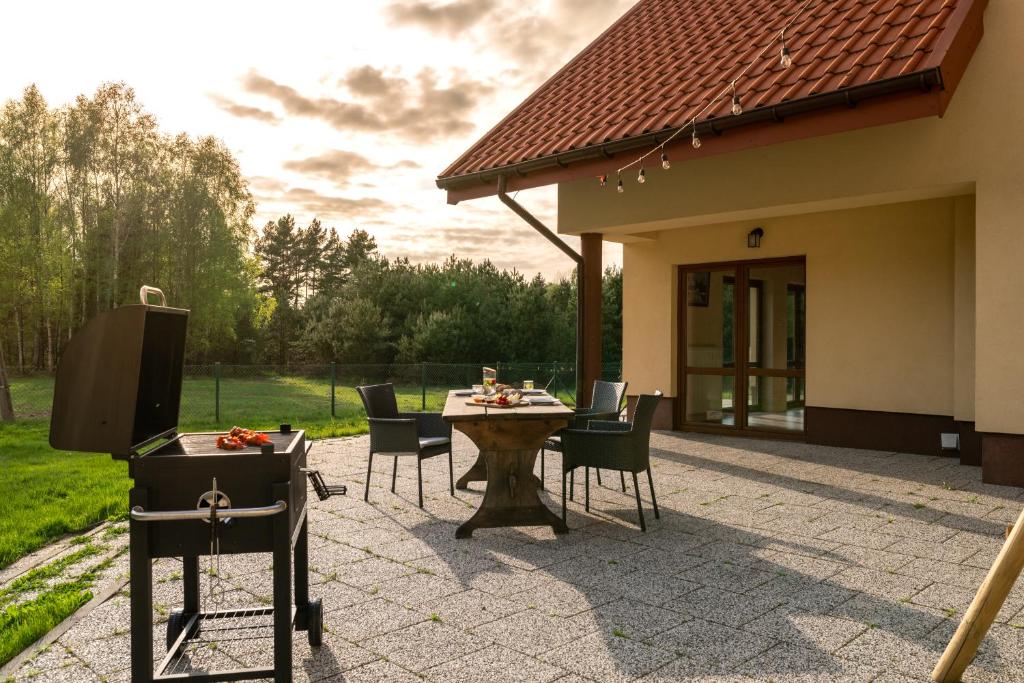 eine Terrasse mit einem Tisch und Stühlen sowie ein Haus in der Unterkunft Dom w Wolnicy - Wszystko do pełnego wypoczynku! 