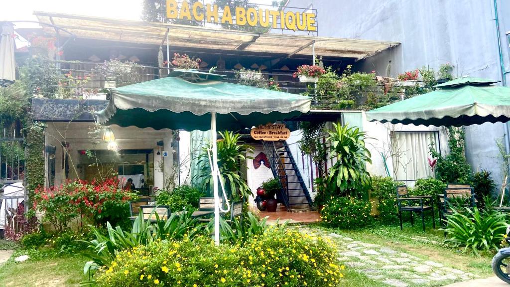 una casa con sombrilla, sillas y plantas en Bac Ha Boutique Homestay, en Bắc Hà