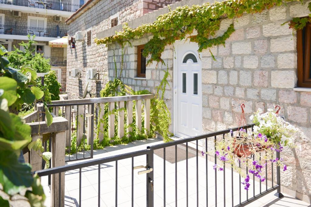 a white door on a stone building with flowers at Kazanegra Exclusive Apartments in Sveti Stefan