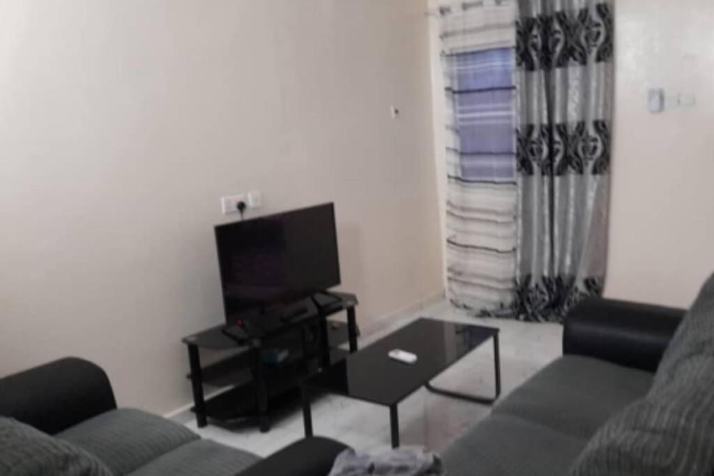 Bambino Guest House في Brikama: غرفة معيشة مع أريكة وتلفزيون بشاشة مسطحة