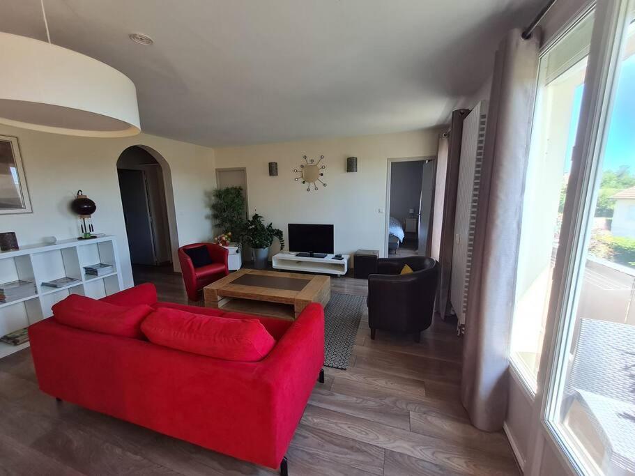 a living room with a red couch and a table at Bel appartement tout proche du Mont st Michel in Pontorson