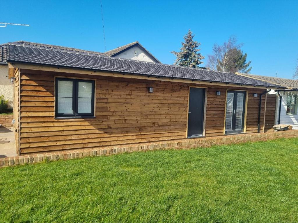 una casa de madera con un patio delante en The Birch Lodge located in Pegsdon en Hexton