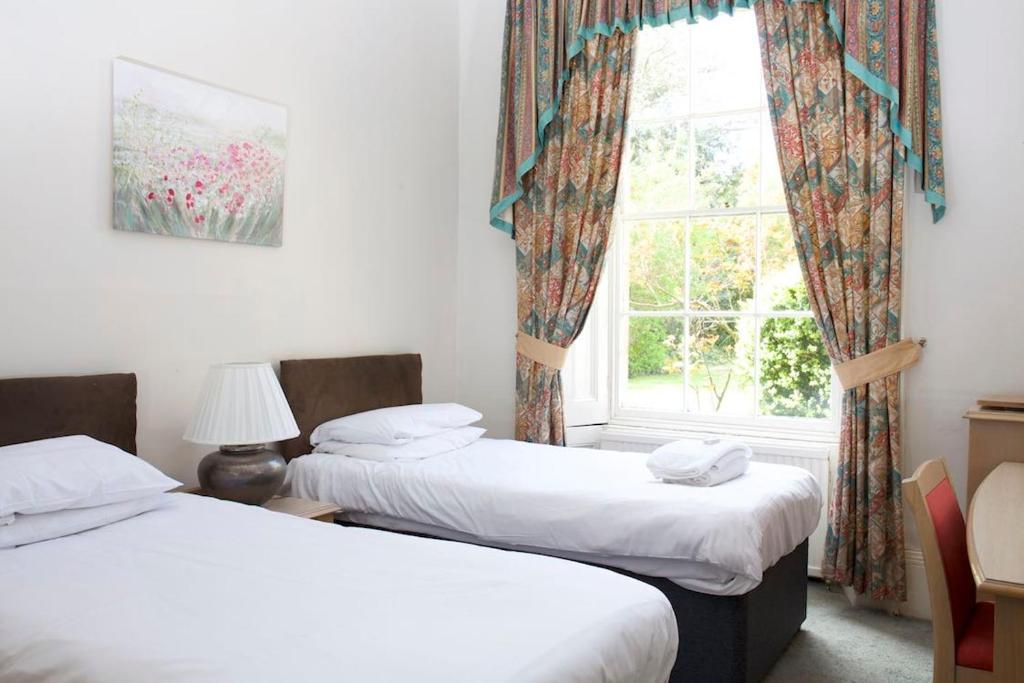 2 camas en una habitación con ventana en Garden House Stamford en Lincolnshire