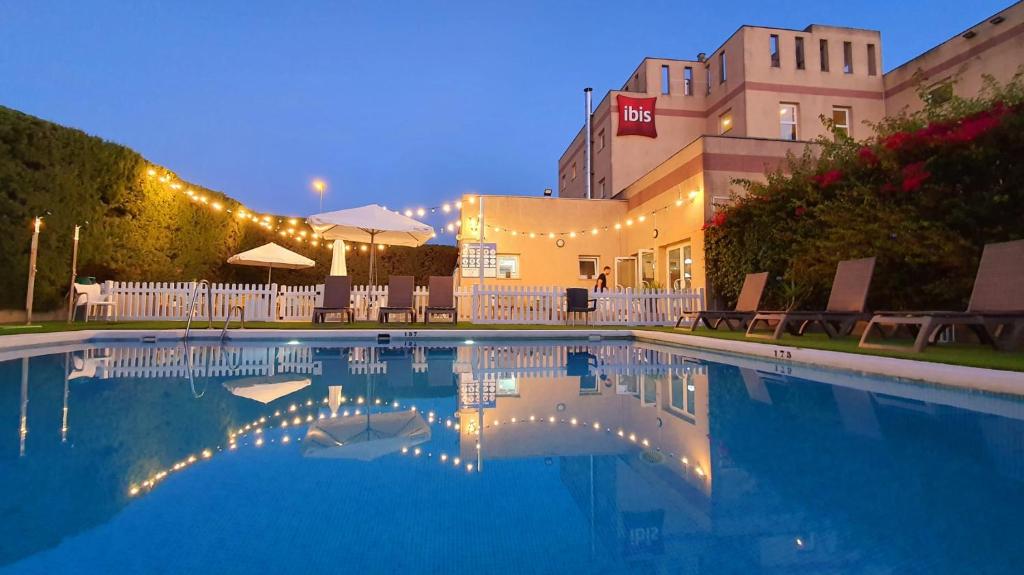 a swimming pool at night with lights on a building at Ibis Jerez De La Frontera Cadiz in Jerez de la Frontera