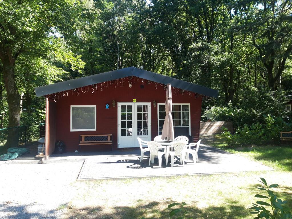 拉納肯的住宿－Vakantiehuisje，前面有一张桌子和椅子,有一个红色的棚子