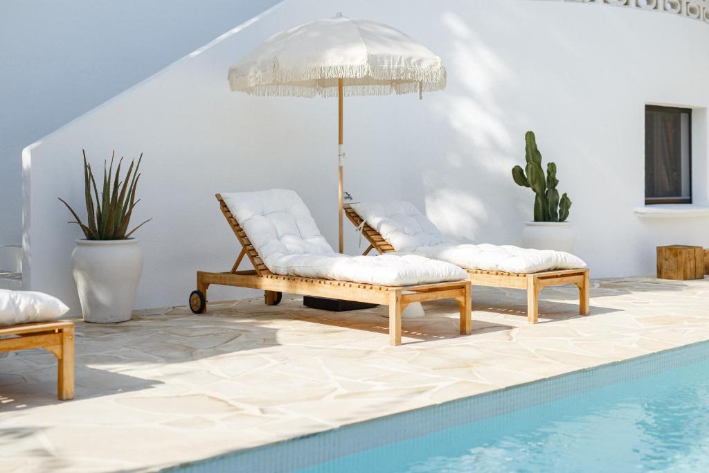 two chairs and an umbrella next to a pool at CASA LUZ - Somewhere south villas by Astrid Elisee in Benitachell