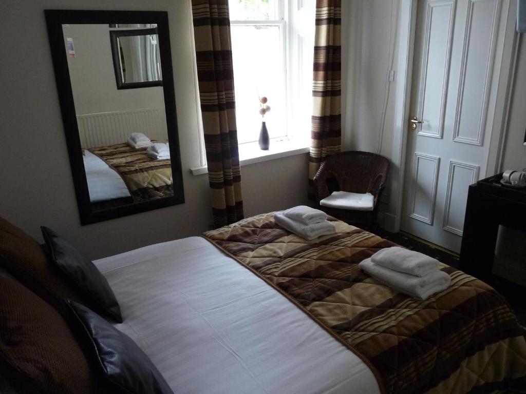 um quarto com uma cama, um espelho e uma janela em The Spinnaker Hotel em Gourock