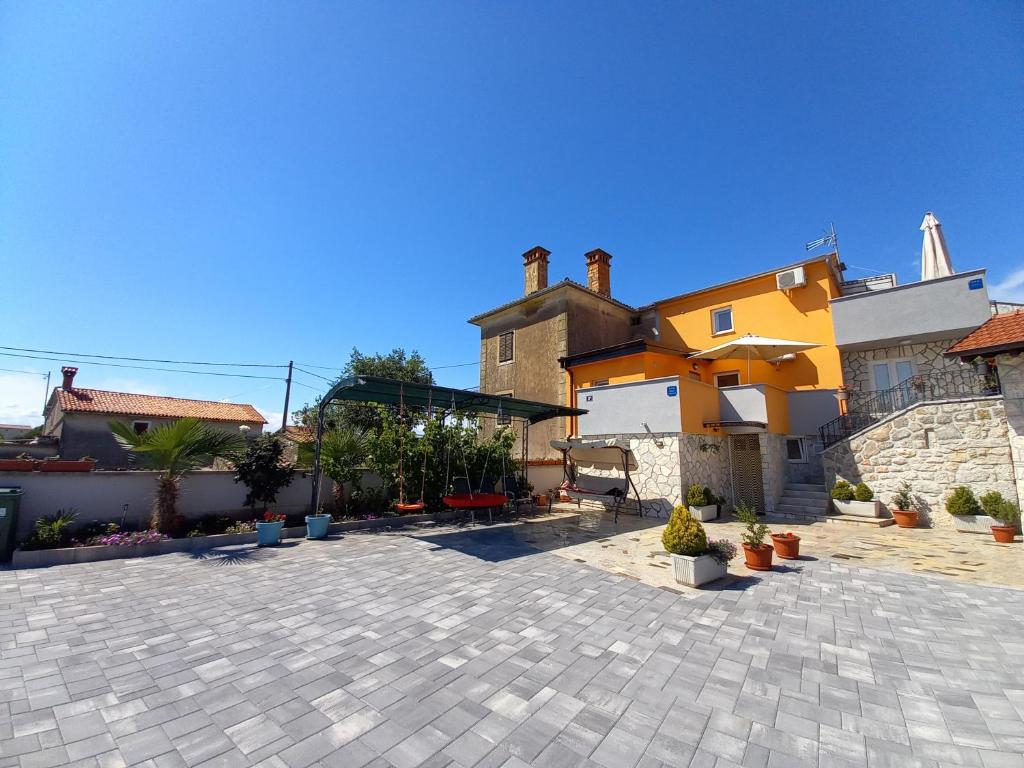 a courtyard with a yellow house and some plants at Apartment & Studio Vrdoljak in Sveti Anton