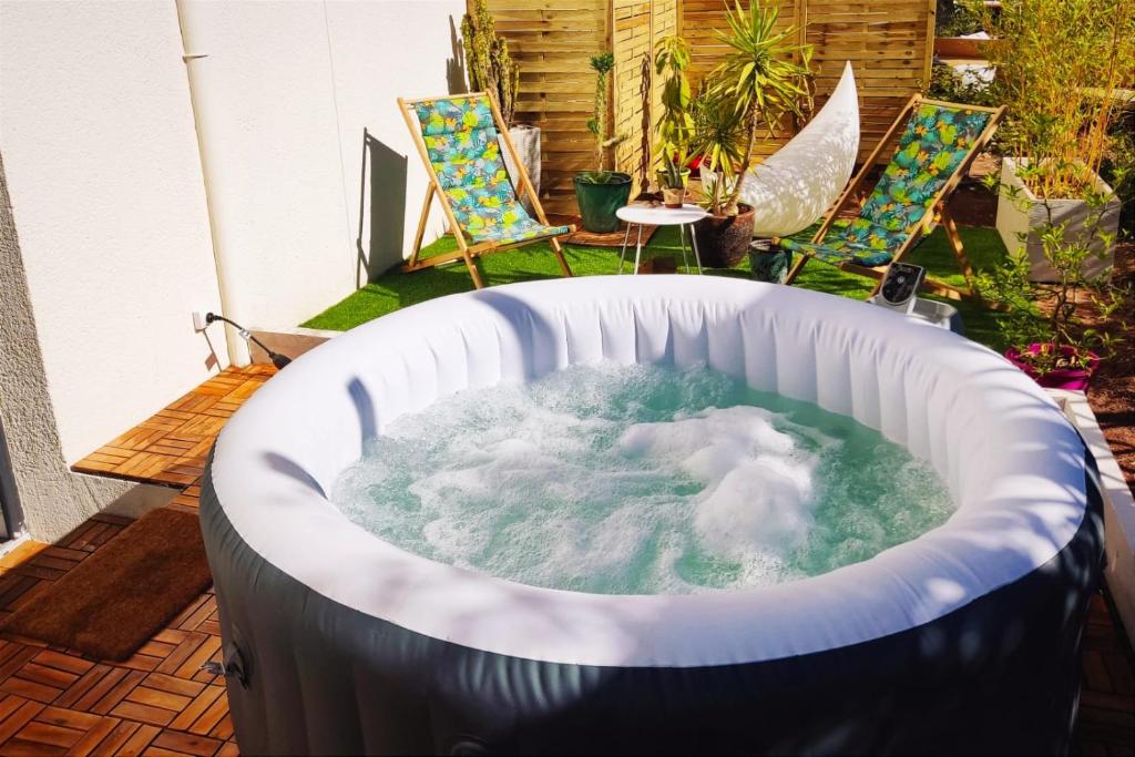 a jacuzzi tub in a backyard with chairs at Superbe appartement avec jacuzzi avec jardin privé in Lyon