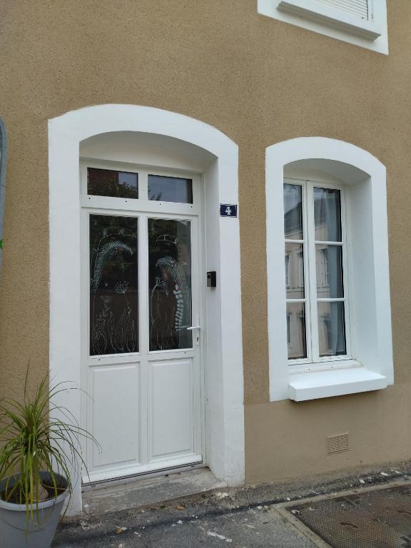 a white door and two windows on a building at La Petite Florentine in Saint-Florent-le-Vieil