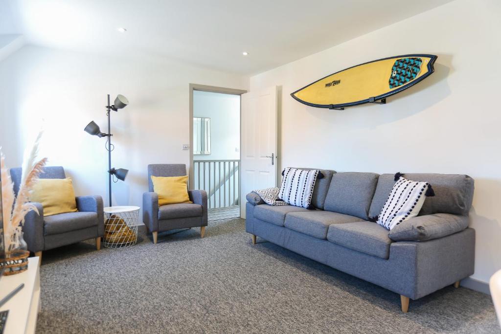 a living room with two couches and a surfboard on the wall at Shorebreak - Bracklesham Bay Apartment in Chichester