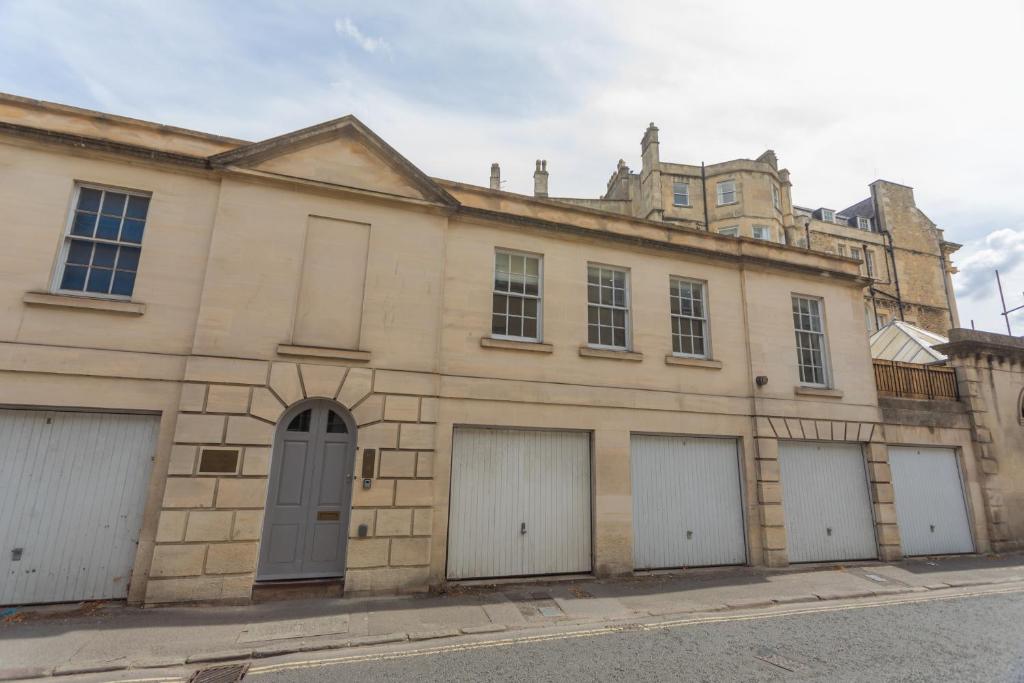 an old stone building with four garages and a castle at Crescent Mews in Bath