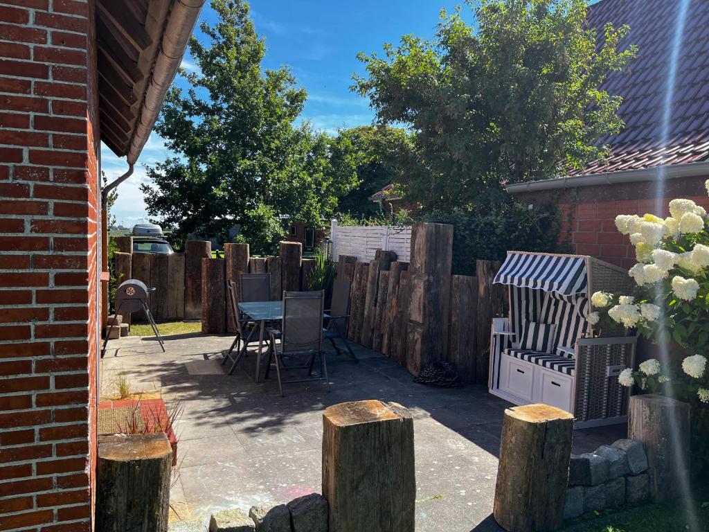 un patio con mesa, sillas y una valla en Ferienhaus Strandperle, en Friedrichskoog