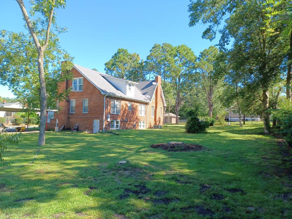 a large brick house in a yard with trees at Brick House Retreat in Rockingham