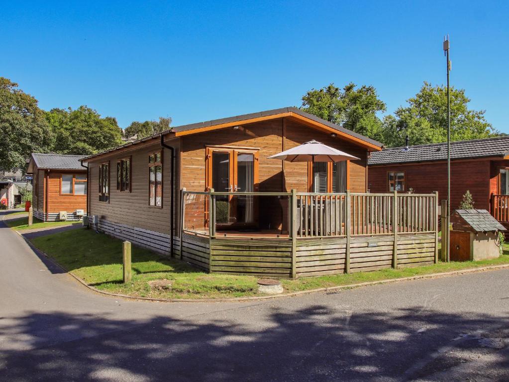 a small house with a porch and an umbrella at Daffodils Lodge in Bowness-on-Windermere