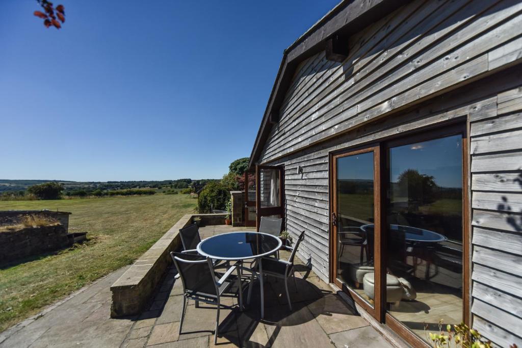 a patio with a table and chairs on the side of a building at Amber Cabin in Ashover