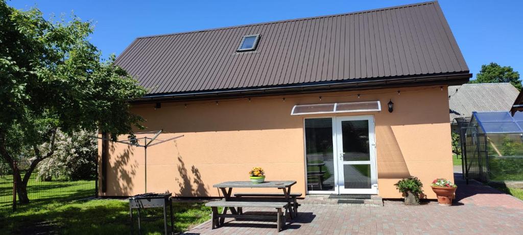 a small house with a picnic table in front of it at Kaltenes Liepziedi in Roja