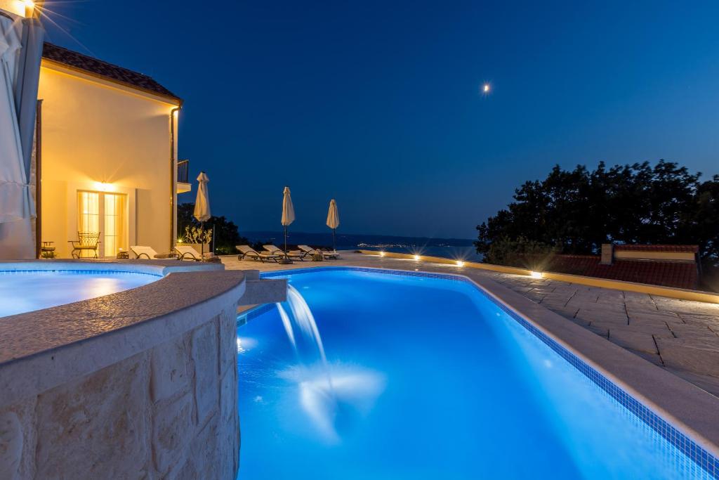 a swimming pool in a villa at night at Villa La Residenza - Heated pool in Podstrana