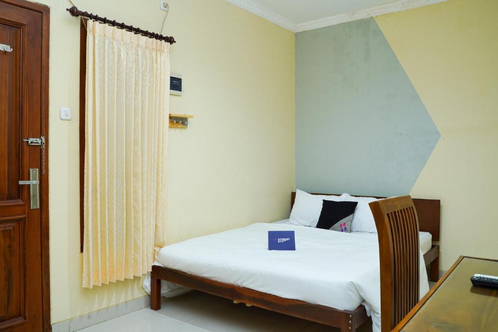 - une chambre avec un lit et un bureau avec un livre dans l'établissement Singgahsini Jemursari, à Djetak