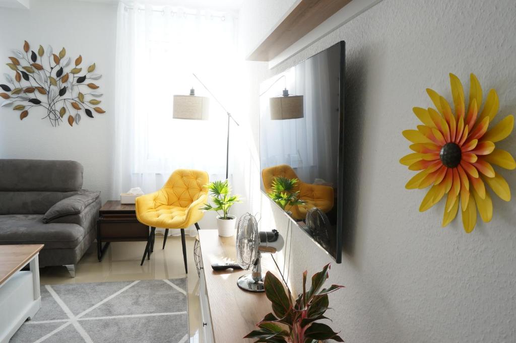 a living room with a mirror and a yellow chair at Mein Apartment Flowers mit Klima, bis 10 Personen in Frankenthal