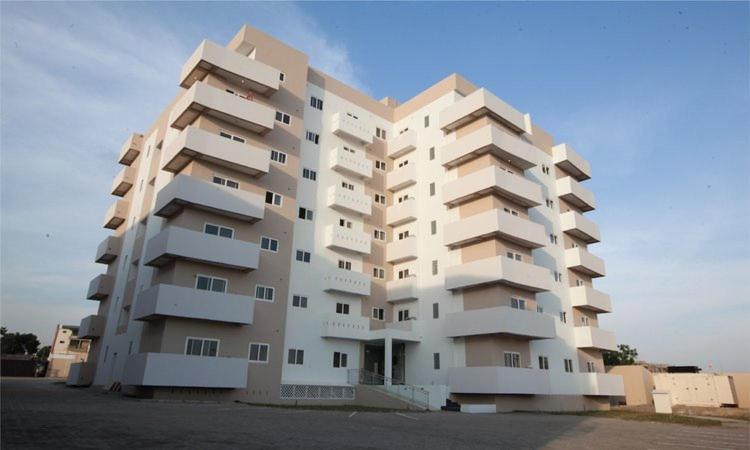 Adrich Properties East Legon في إيست ليغون: مبنى شقق بيضاء كبيرة في موقف للسيارات