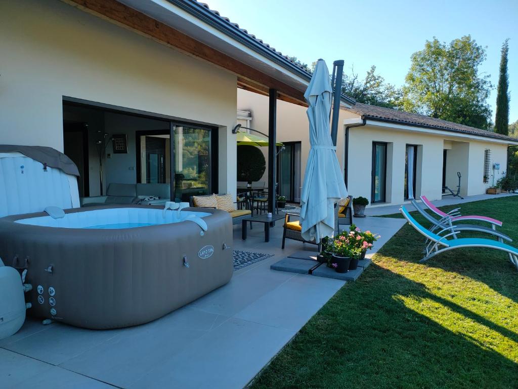 a backyard with a hot tub and an umbrella at Villa Contemporaine Climatisée classée 4 étoiles - Vue panoramique sur la Vallée d'Orb et le Caroux in Bédarieux