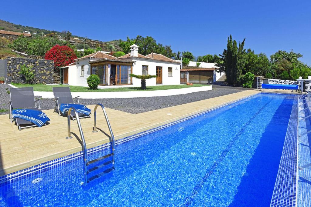 una piscina con 2 sillas y una casa en Casa El Roquito en Lodero
