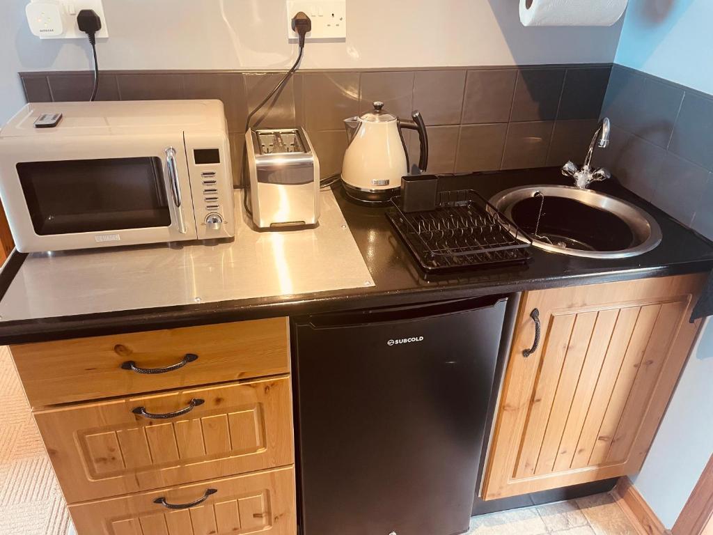 um balcão de cozinha com um lavatório e um micro-ondas em The Rowanberry Suite at Rowan Cottage em Elgol