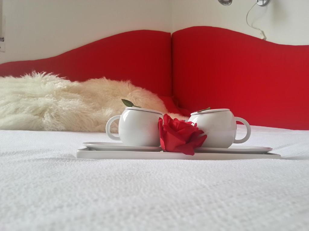 zwei weiße Tassen und eine rote Rose auf dem Bett in der Unterkunft Appartamento Lily in Florenz