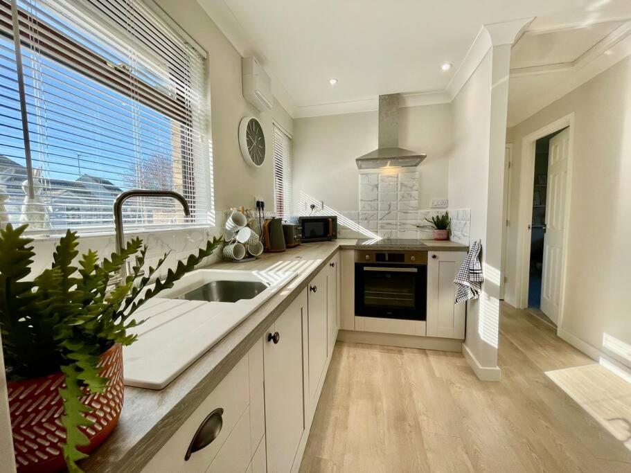 a white kitchen with a sink and a window at Charming 2 Bedroom Bungalow with open plan living in Felixstowe