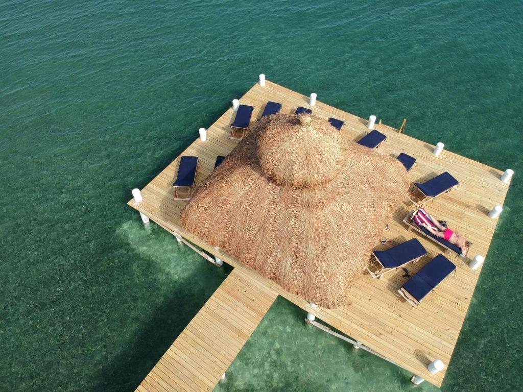 a dock with chairs and a straw roof on the water at VeLento Oceanfront Penthouse #1 in Caye Caulker