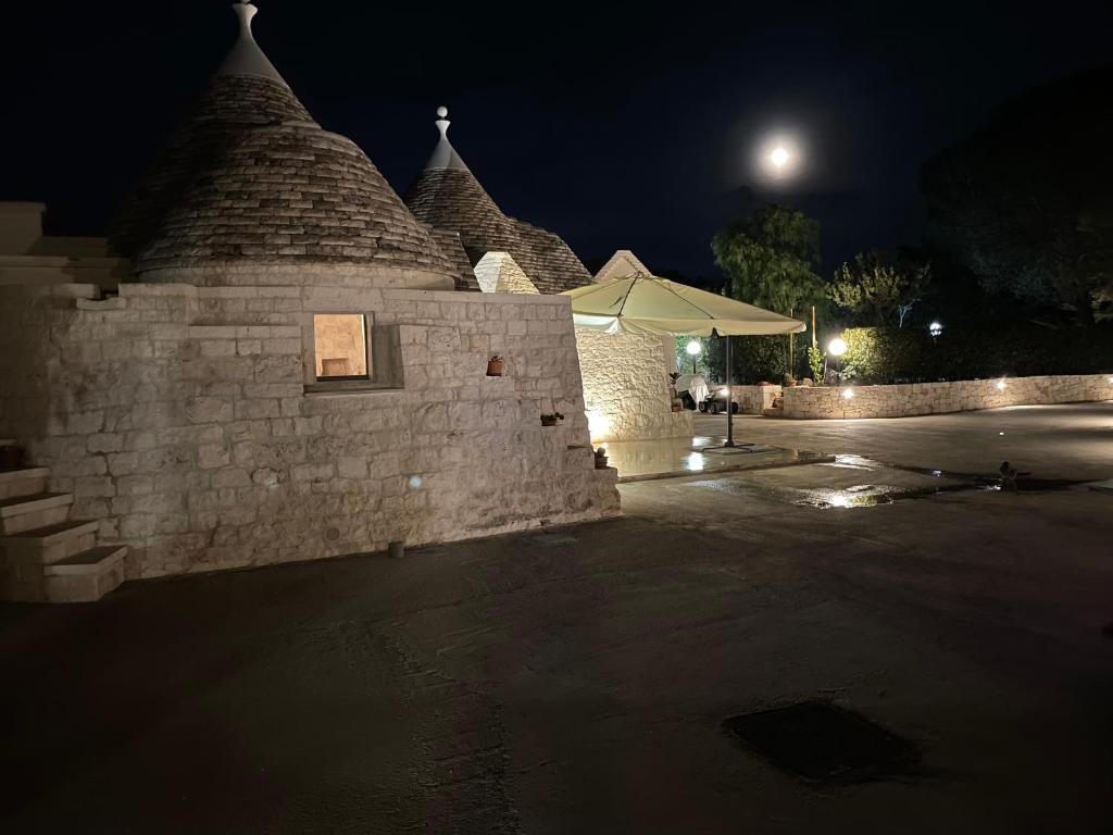 un muro di pietra con un ombrello accanto di notte di La Valle dei Trulli Relais a Martina Franca