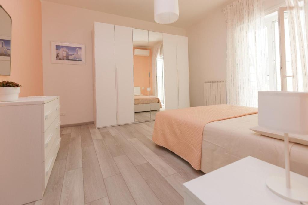 ein weißes Schlafzimmer mit einem Bett und einem Spiegel in der Unterkunft Casa di Dani (città 011015-LT-2232) in La Spezia