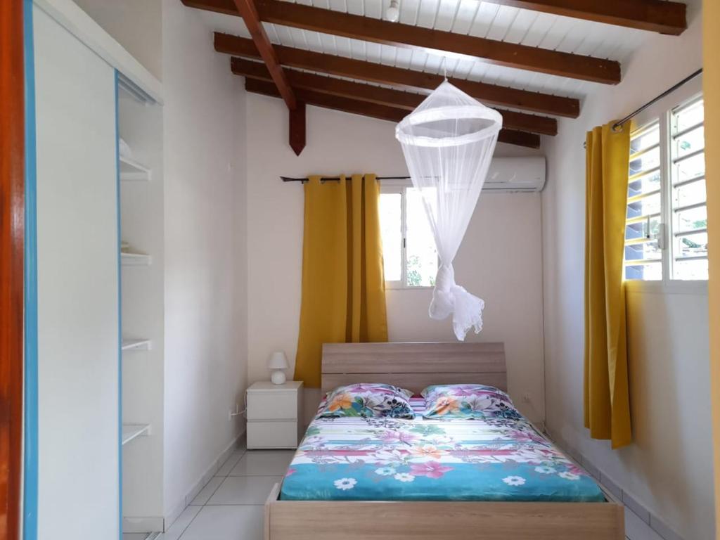 a bedroom with a bed and a window with yellow curtains at Paradyse Den's près Sources d'Eau Chaudes , Paisible , Vue sur mer , WIFI in Bouillante