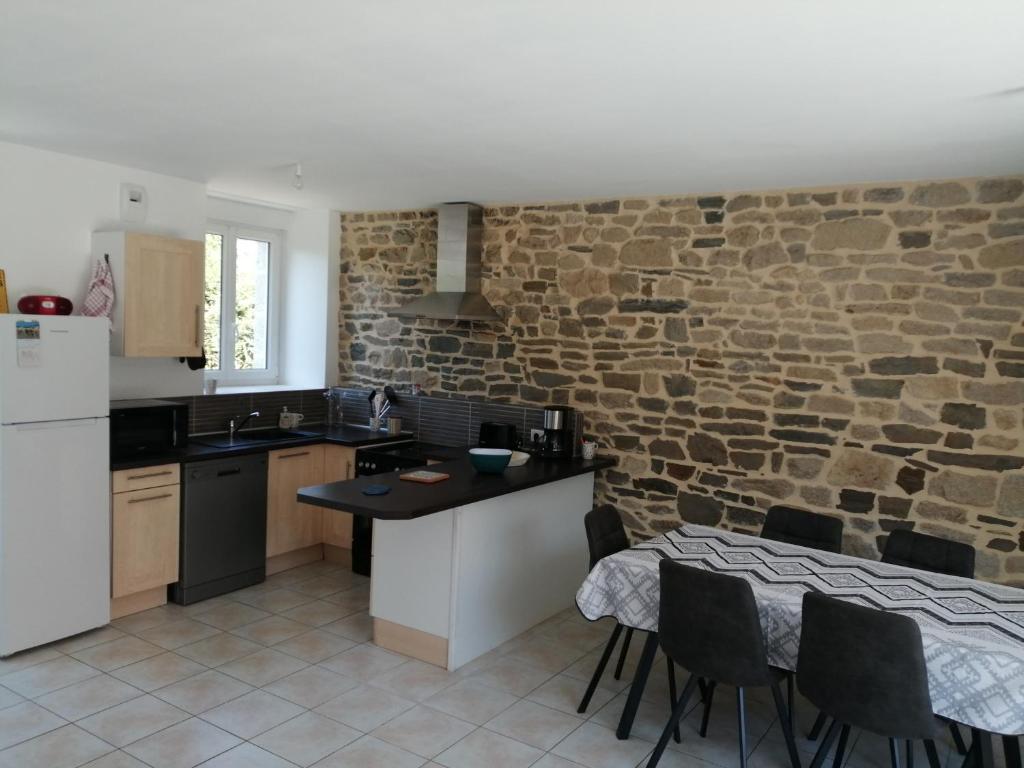 uma cozinha com uma parede de pedra e uma mesa e cadeiras em Maison Jullouville au calme em Jullouville-les-Pins