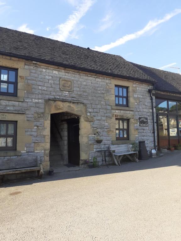 a stone building with a bench in front of it at The Hayloft in Hartington