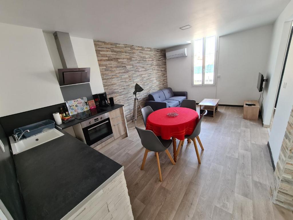 cocina y sala de estar con mesa roja en Appartement 60m2 rdc avec jardin en Saint-Génis