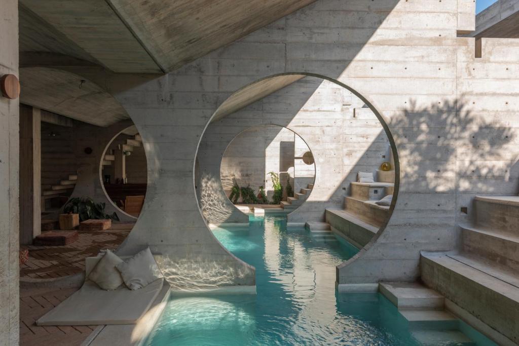 a pool of water in a building with two circular mirrors at Casa TO in Puerto Escondido