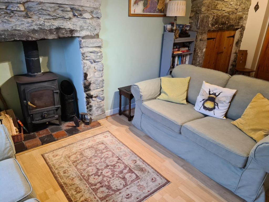 ein Wohnzimmer mit einem blauen Sofa und einem Holzofen in der Unterkunft North Wales Cosy Cottage with views near Eryri Snowdonia in Nantlle