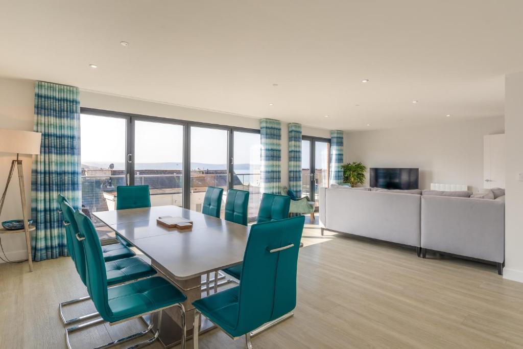 a dining room with a table and blue chairs at 8 Challacombe - Luxury Apartment at Byron Woolacombe, only 4 minute walk to Woolacombe Beach! in Woolacombe