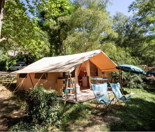 une tente avec 2 chaises, une table et un parasol dans l'établissement Camping Onlycamp Le Petit Bocage, à Les Essarts