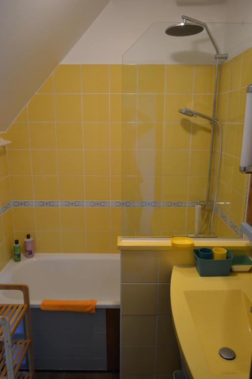 uma casa de banho amarela com uma banheira e um lavatório em La Maison Rose em Fort-Mahon-Plage
