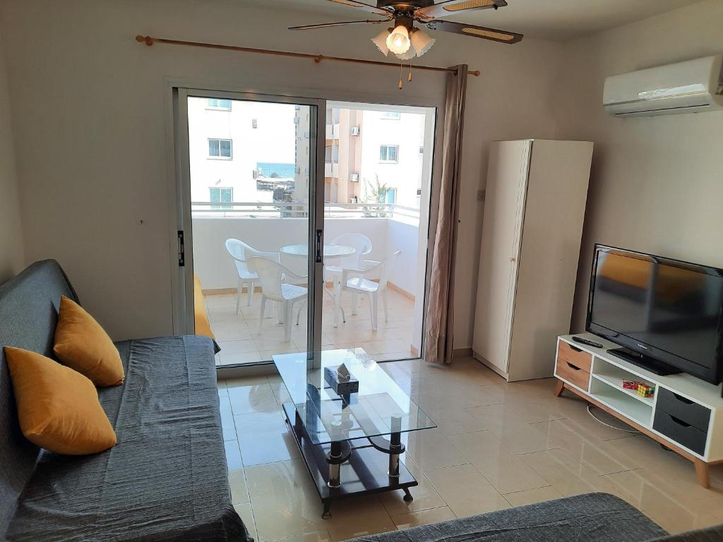 - un salon avec un canapé, une télévision et une table dans l'établissement Large apt 2 bedrooms sea view & 2 balconies, à Larnaka