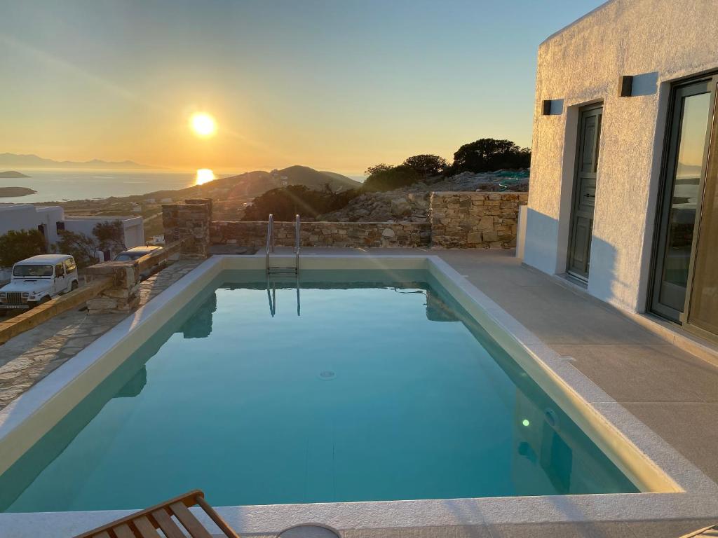 a swimming pool with a sunset in the background at Deja Blue Villa 1 in Agios Georgios