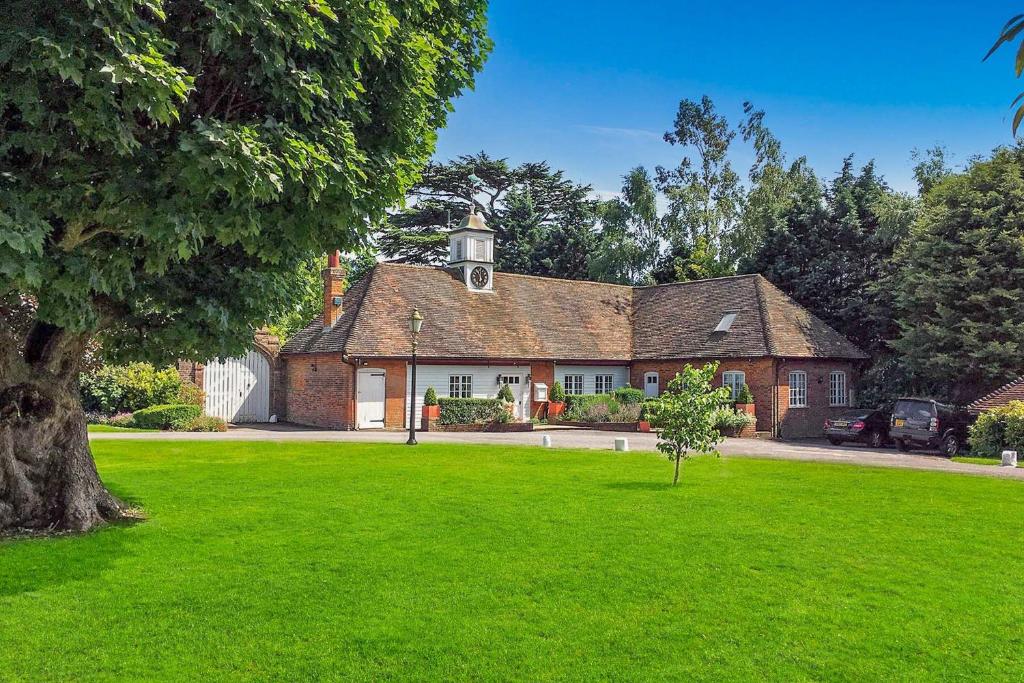 una vieja casa de ladrillo con un césped verde delante de ella en The Coach House by Bloom Stays, en Harrietsham