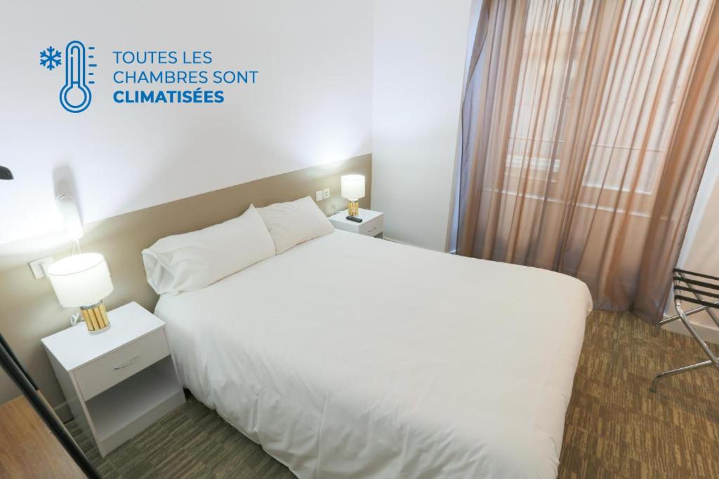 ロデーズにあるホテル デュ クロシェの白いベッドと窓が備わるホテルルームです。