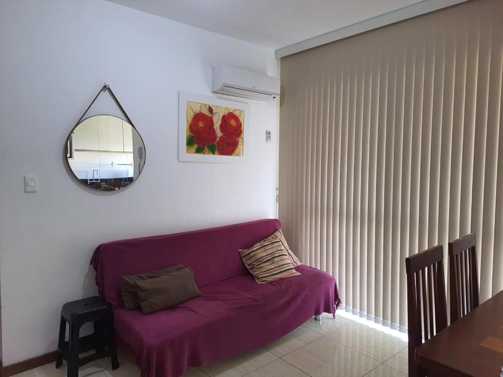 APARTAMENTO ENCANTADOR, À 400 METROS DA PRAIA DE PALMAS, في جوفيرنادور سيلسو راموس: غرفة معيشة مع أريكة أرجوانية ومرآة