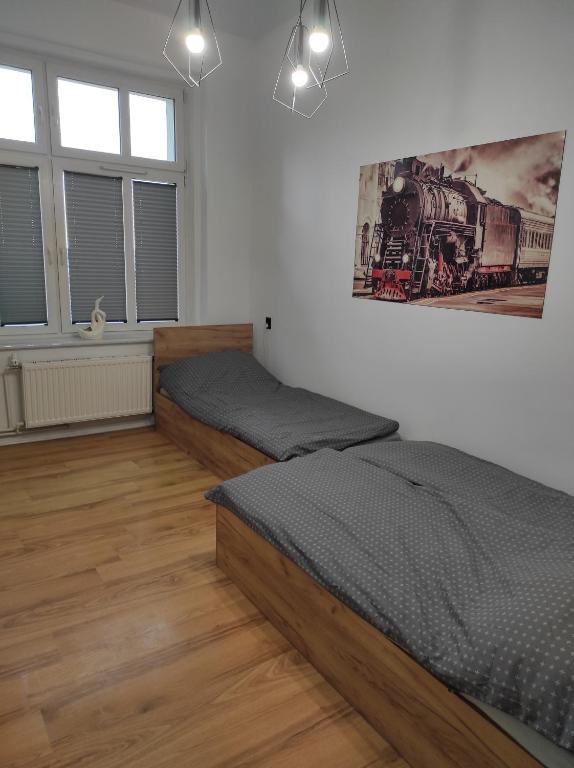 Apartament "Przy Dworcu" في خوينيتسا: غرفة نوم بسريرين ولوحة على الحائط